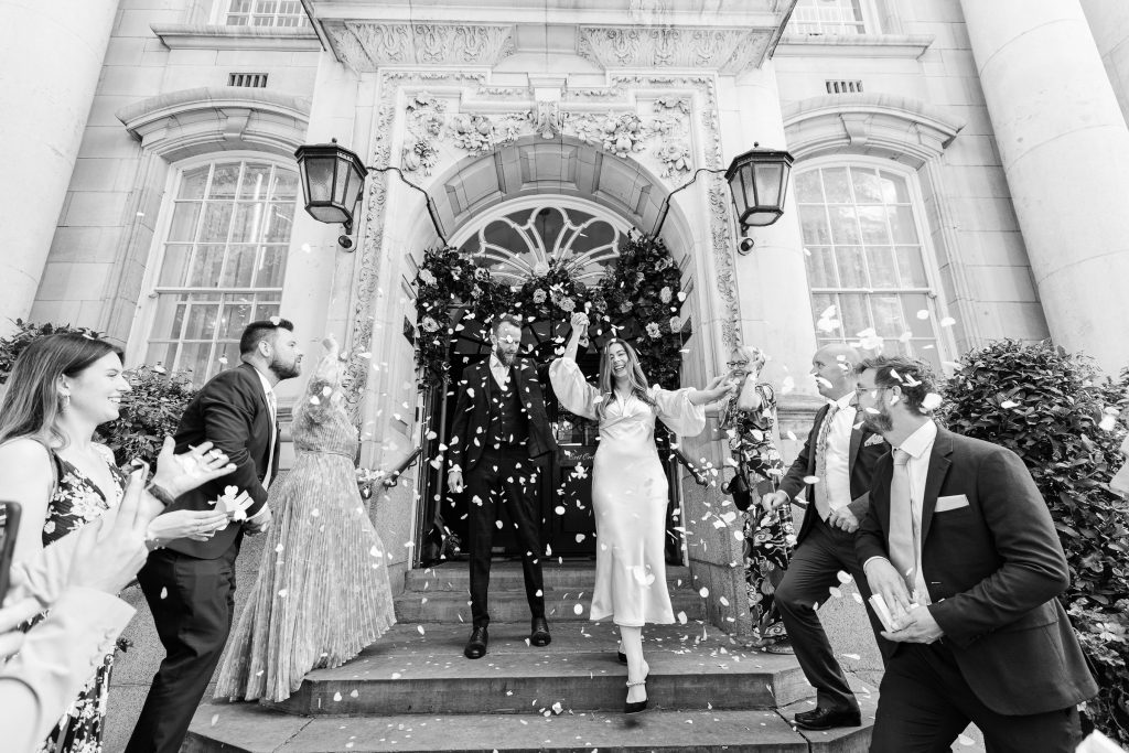 Couple walking through confetti at Chelsea Town Hall